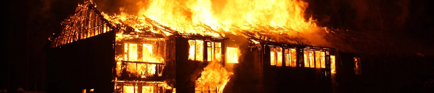 Bannière avec photo d’un bâtiment en flamme dans la nuit.