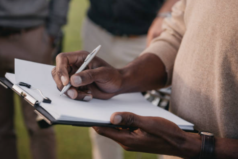 Photo de mains tenant un bloc-notes et inscrivant des choses dedans avec un stylo. 